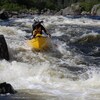 Une personne dans un kayak jaune descend les rapides.