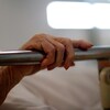 Un patient tient la barre métallique de son lit d'hôpital.