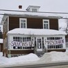 Une banderole sur laquelle les mots « Sauvons la maison brune » est accrochée sur la façade de la maison en papier brique, en hiver.