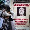 Deux manifestants se prennent dans les bras, derrière une pancarte du président iranien où il est écrit assassin. 