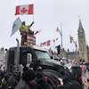 Des manifestants sur un camion brandissent des drapeaux devant le parlement d'Ottawa.