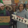 Une poignée de jeunes adolescents scandent un slogan en tenant des panneaux contre la pollution et en faveur de la planète. 