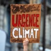 Une personne tient une pancarte sur laquelle on peut lire : « Urgence climat ».