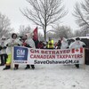 Photo d'hommes à l'extérieur dans la neige tenant une banderole où on peut lire : « GM a trahi les contribuables canadiens ».