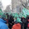 Une foule de manifestants brandissant des drapeaux aux couleur du Front commun intersyndical en hiver devant l'Assemblée nationale.