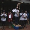 Des manifestants dans la rue ont tous les yeux bandés d'un ruban noir. Ils simulent une pendaison.