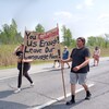 Des jeunes marchent sur une route en brandissant une pancarte.