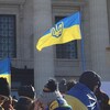 Des personnes sont rasemblées et brandissent des drapeaux de l'Ukraine