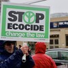 Un homme brandit une pancarte sur laquelle sont écrits les mots « Stop ecocice change the law ».