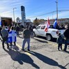 Des manifestants écoutent un discours en brandissant des drapeaux du Québec et du Canada.