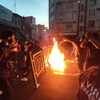 Des Iraniens allument un feu au milieu d'une rue de Téhéran.