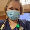 Un infirmière en uniforme se prends en photo avec son masque sanitaire. 