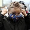 Un enfants installe son masque sur son visage espiègle.