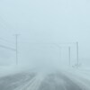 Un rue déserte, assombrie et brouillée par les forts vents qui déplacent la neige. 