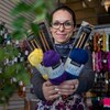 Mélissa Bolduc-Desrochers au milieu de sa boutique de tricot. Elle tient dans ses mains des aiguilles à tricoter et des balles de laine.