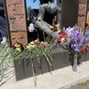 Des gerbes de fleurs déposées sur un monument commémoratif.