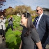 Une femme marche à côté d'un garde de sécurité pendant que des gens la photographient. 