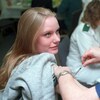 Une jeune femme lève les yeux vers une infirmière qui lui administre un vaccin.