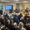 Des citoyens assistent à une présentation publique d'un projet de camping dans la salle du conseil municipal.