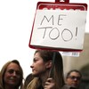 Une femme de profil dans une manifestation, dressant une pancarte sur laquelle les mots « Me Too! » sont écrits.