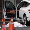 Un corps couvert d'un linceul à côté d'une voiture.