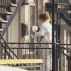 Une femme vêtue d'une combinaison blanche entre dans l'appartement avec un appareil photo.