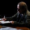 L'écrivain Michel Houellebecq signant un livre sur une table.