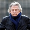 Photo de Roman Polanski vêtu d'un manteau de cuir, prise à l'extérieur.
