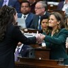 Chrystia Freeland remet une pile de documents à une page du Parlement.