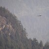Un hélicoptère survole une forêt enfumée