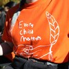 Une personne portant un habit orange avec le logo du mouvement Every Child Matters 
