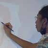 Maria Tonta en train de dessiner sur le mur où le dessin est projeté. 