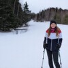 La jeune femme au pied d'une pente de ski.