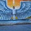 Un garçon habillé d'un costume blanc porte des ailes d'ange.  