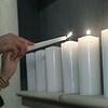 Deux mains tenant une chandelle allument des bougies lors de la cérémonie. 