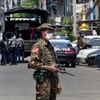 Un soldat birman porte une arme automatique, et scrute les alentours dans une rue achalandée.