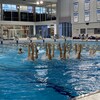 Des nageuses sortent les jambes de l'eau en même temps dans un piscine.
