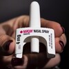 Une main tient le spray nasal Narcan.