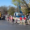 Des enfants marchent main dans la main, près de deux autobus jaunes.