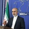 Nasser Kanani en conférence de presse à côté d'un drapeau iranien.