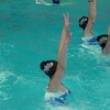 Un homme dans une piscine fait de la natation artistique avec des coéquipières.
