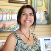 Une femme sourit devant des tableaux d'arts autochtones