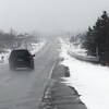 Une voiture qui roule sur une route bordée de neige.