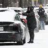 Des personnes déneigent des automobiles. 