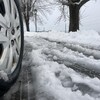 Un pneu à neige de voiture roule sur une route couverte de gadoue.