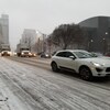 Photo de voitures qui roulent sur un boulevard enneigé.