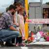 Les gens se recueillent devant un mémorial où des fleurs sont déposées. 