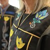 Un homme et une femme sont vêtus de toges ornées de perles et de broderies en forme de fleurs. 