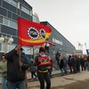 Un groupe de personnes brandissent des drapeaux lors d'une ligne de piquetage devant l'Assemblée législative du Nunavut, le 26 mai 2023.
