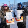 Deux personnes brandissent des pancartes dans une rue enneigée d'Iqaluit, le 17 mars. 